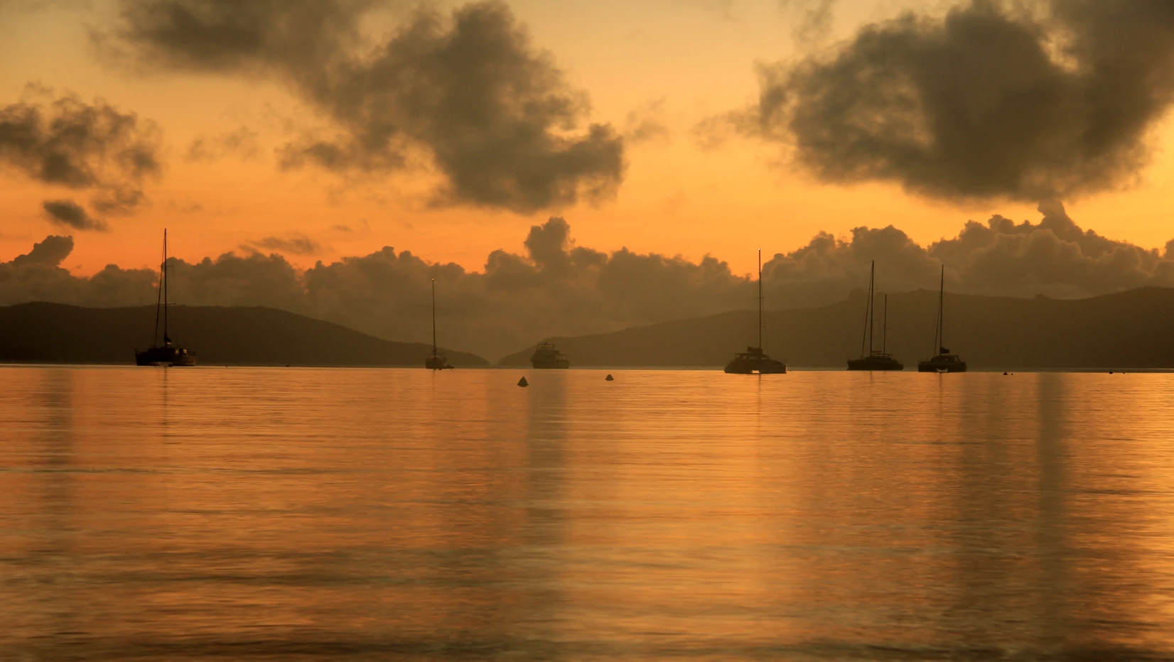 Sail boats anchored in bay at sunrise.